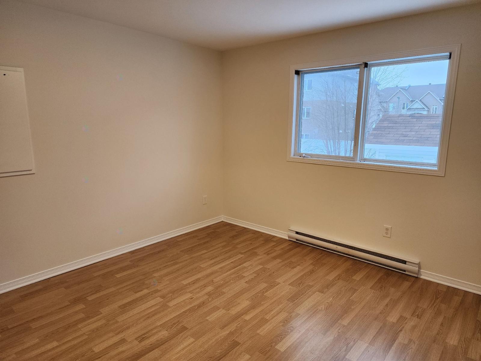 A room with a window and a radiator on the floor.