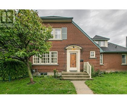 A red brick house with a white door and a tree in front.