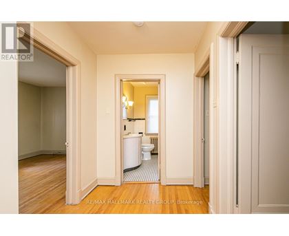 A hallway with a toilet and sink visible through the door.