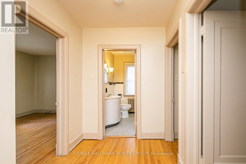 A hallway with a toilet and sink visible through the door.
