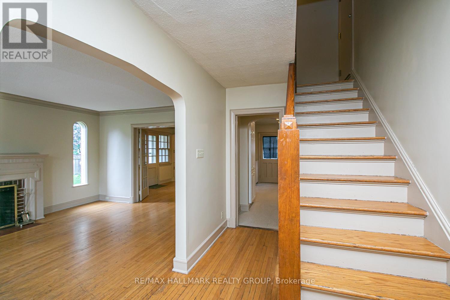 A staircase with wooden steps and handrail in a room with white walls and wooden flooring.
