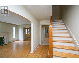 A staircase with wooden steps and handrail in a room with white walls and wooden flooring.