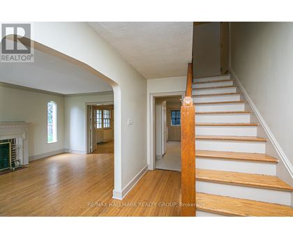 A staircase with wooden steps and handrail in a room with white walls and wooden flooring.