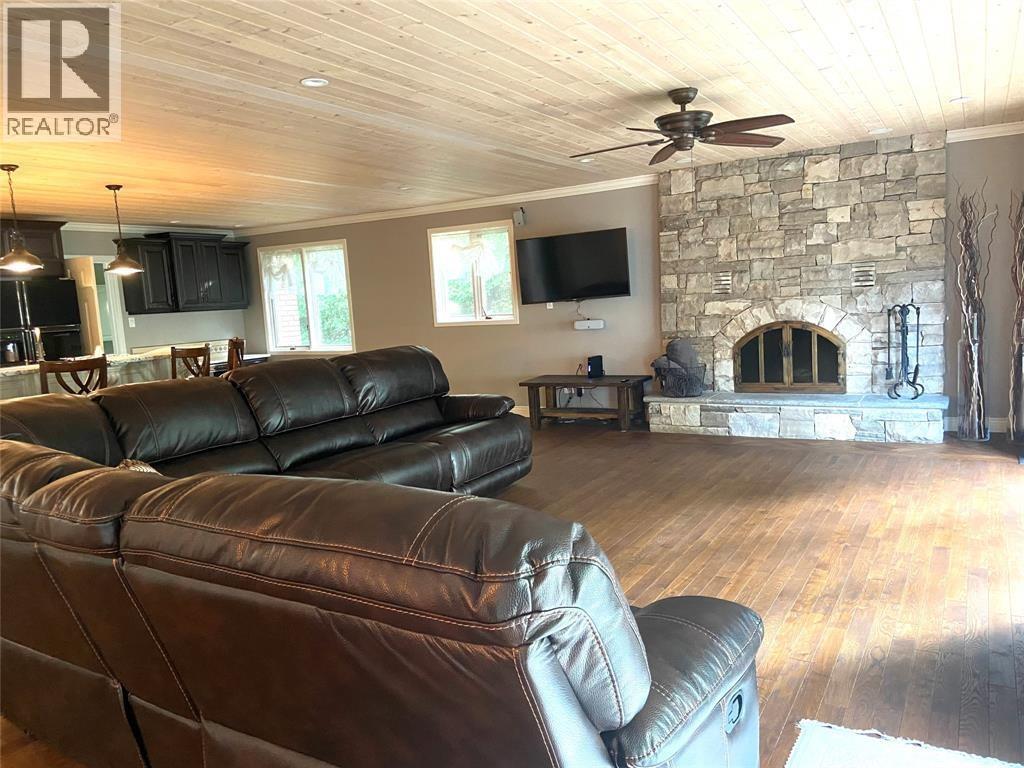 A living room with a stone fireplace and a stone wall.