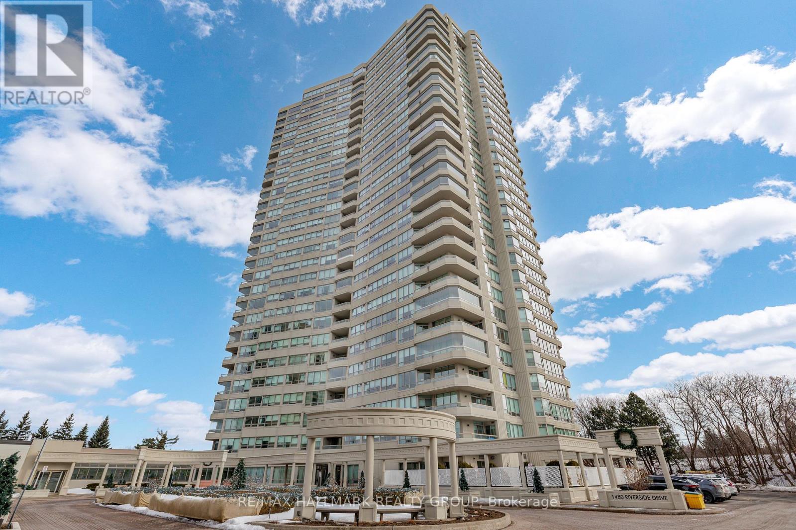 A tall building with a flat roof and a parking lot in front.