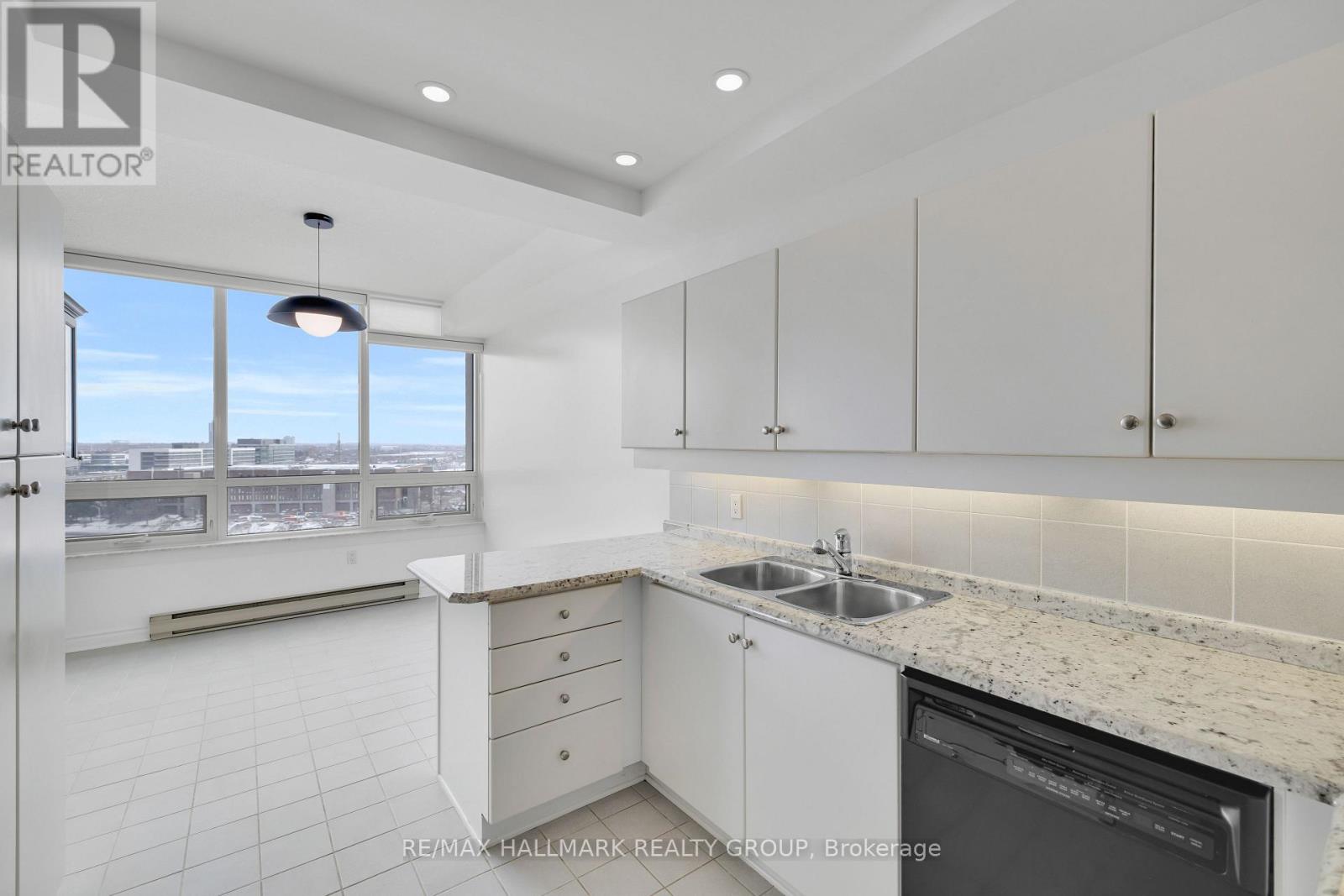 A kitchen with white cabinets and a marble countertop.