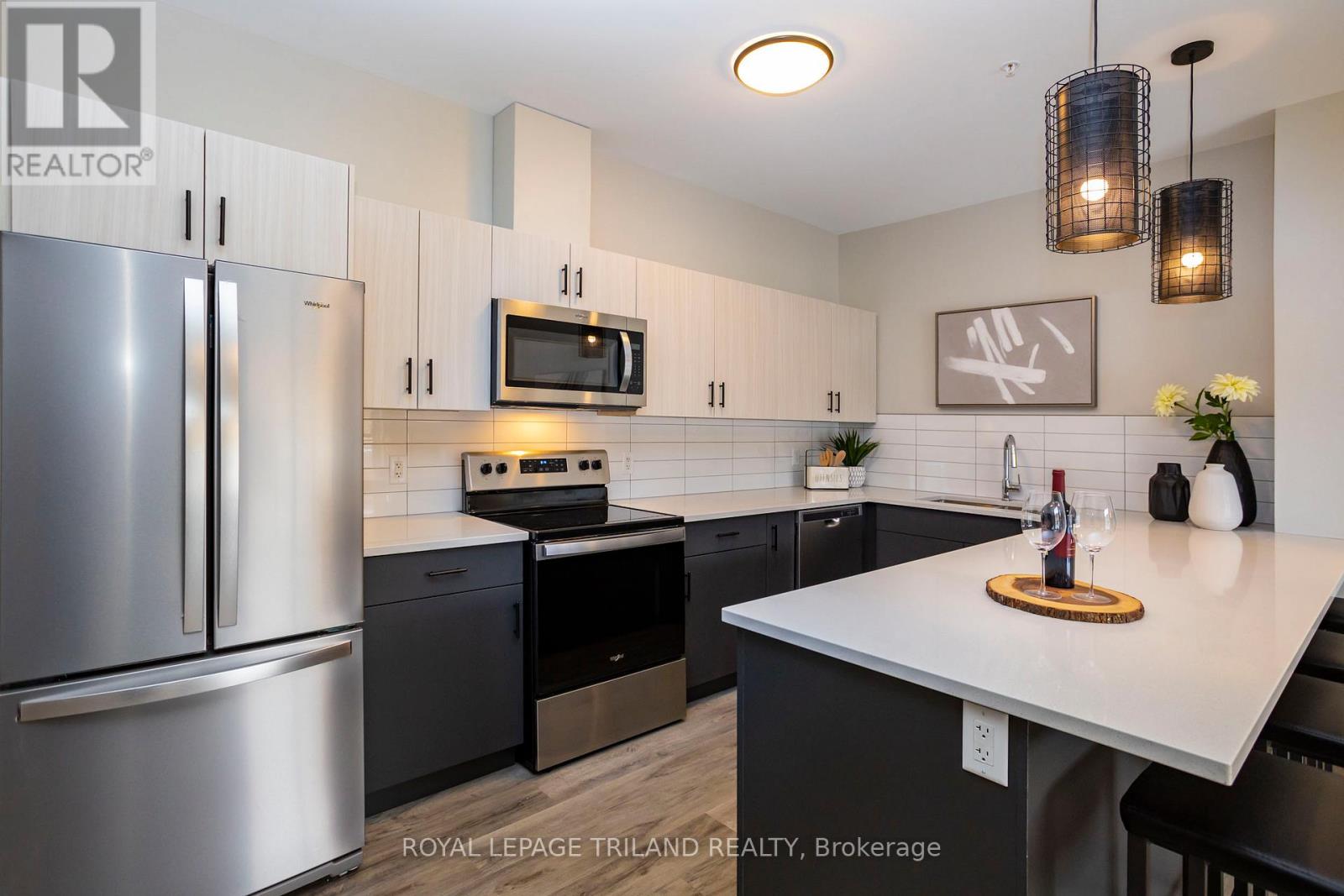 A modern kitchen with a stainless steel refrigerator and black countertops.