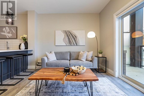 A modern living room with a grey couch, a wooden coffee table, and a large painting on the wall.