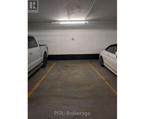 A parking garage with a white car parked on the left and a white car parked on the right.