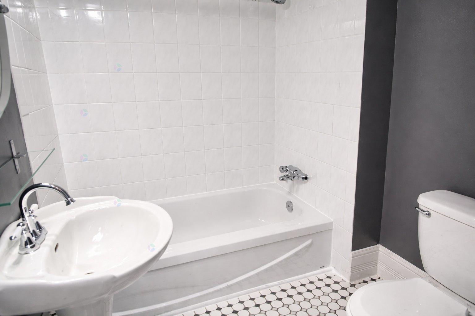 A white sink is on the left of a white bathtub in a bathroom.
