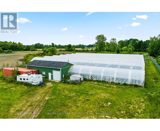 A greenhouse and a red building are situated in a grassy field.