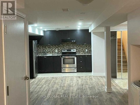 A kitchen with black cabinets and a patterned backsplash is visible from a hallway.