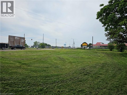 A grassy field with a truck and a building in the distance.
