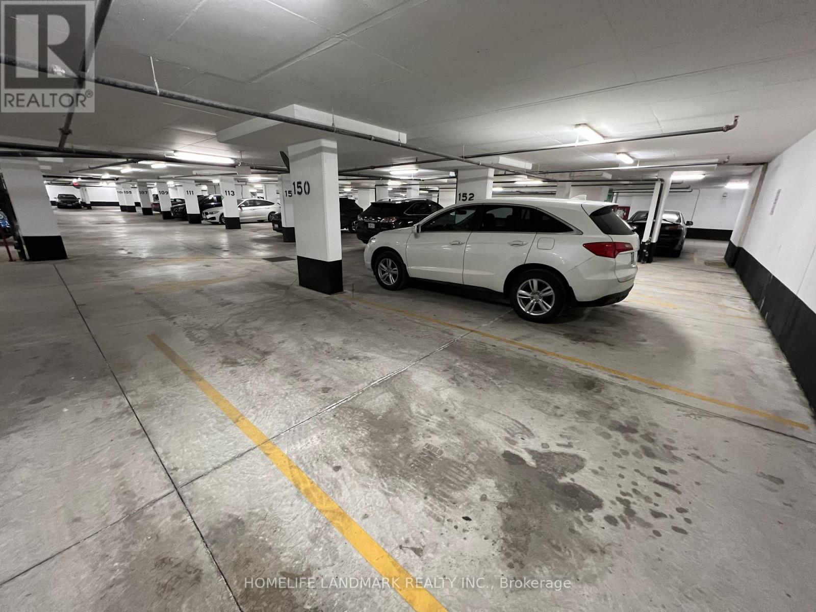 A car is parked in a parking garage with a yellow line on the ground.