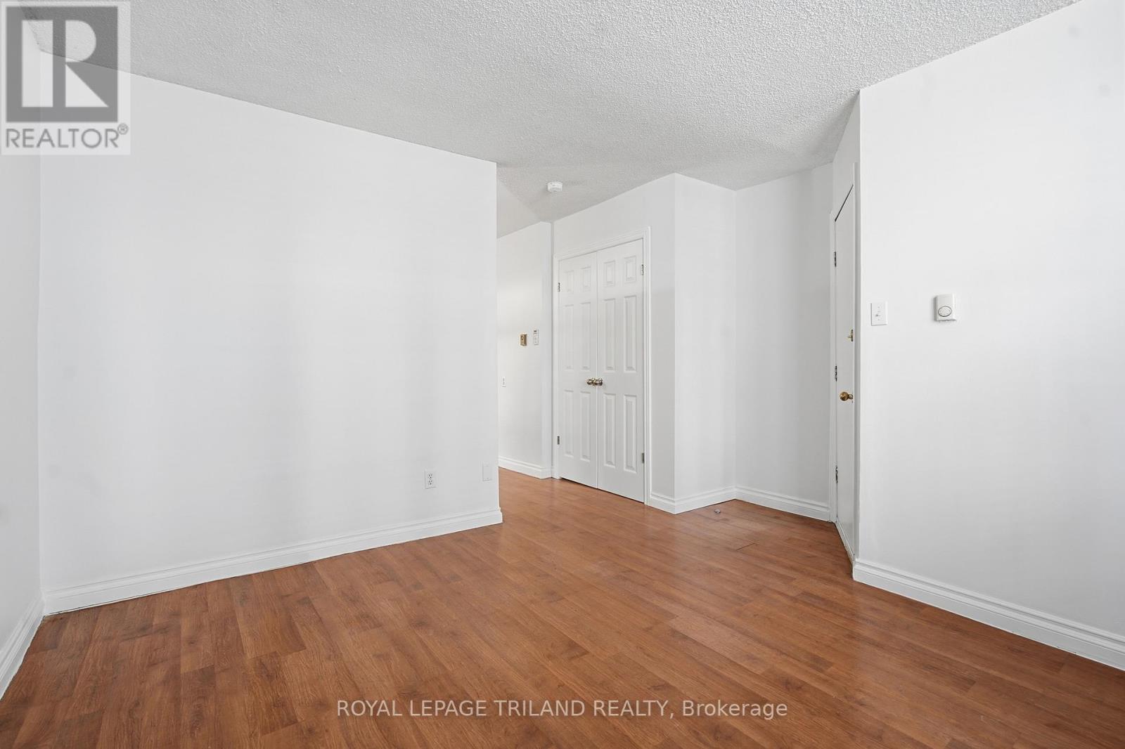 A white room with wooden floors and a doorway leading to another room.
