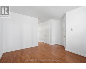 A white room with wooden floors and a doorway leading to another room.