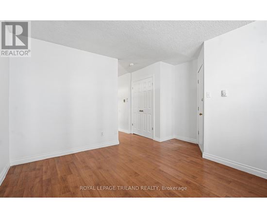 A white room with wooden floors and a doorway leading to another room.