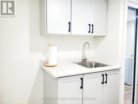 A white kitchen with a sink and cabinets.