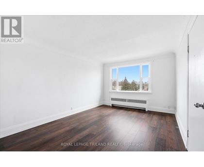 A white room with a window and a wooden floor.