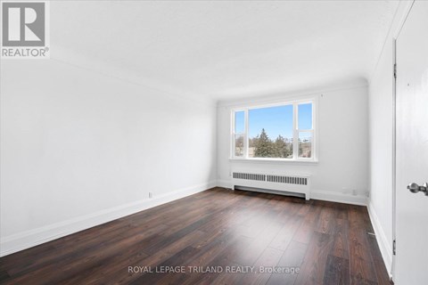 A white room with a window and a wooden floor.