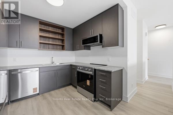 A modern kitchen with dark wood cabinets and stainless steel appliances.