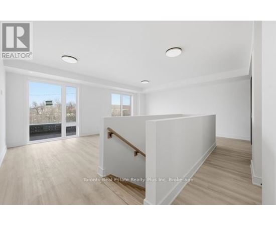A spacious room with a wooden floor and white walls, with a window showing a view of a snowy landscape.