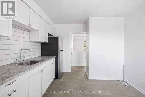 A kitchen with white cabinets and a black fridge.
