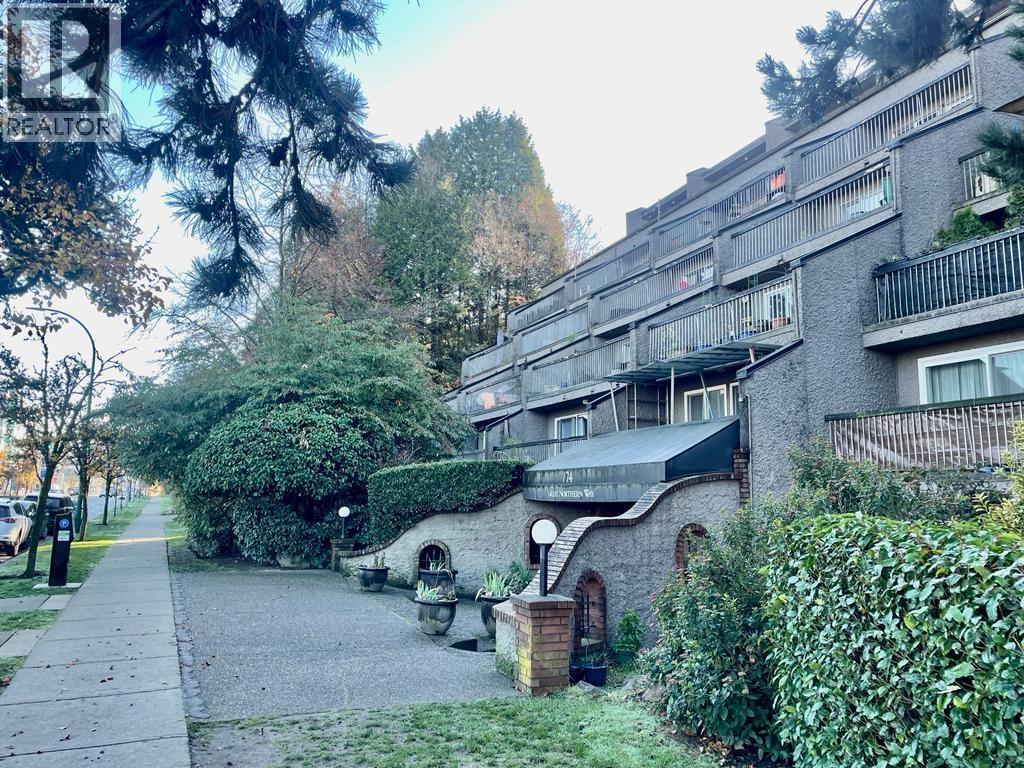 A residential building with a balcony and a small garden in front.