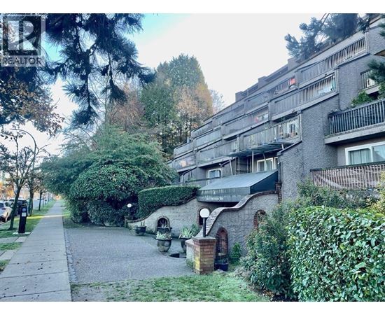 A residential building with a balcony and a small garden in front.