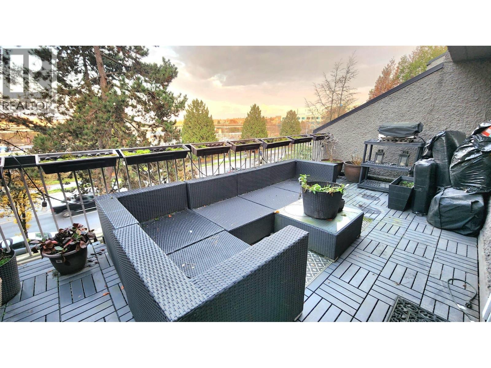 A patio with a grey sofa and a table with a potted plant on it.