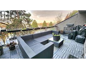 A patio with a grey sofa and a table with a potted plant on it.