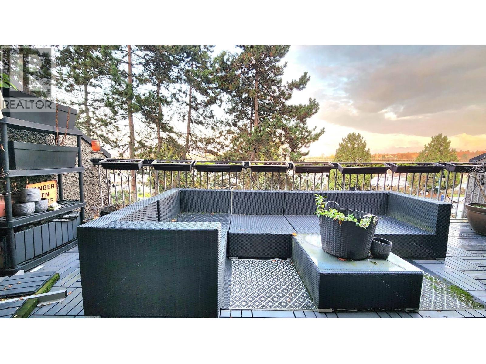 A modern outdoor seating area with a black sofa and table.