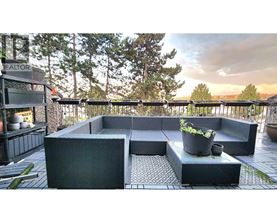 A modern outdoor seating area with a black sofa and table.