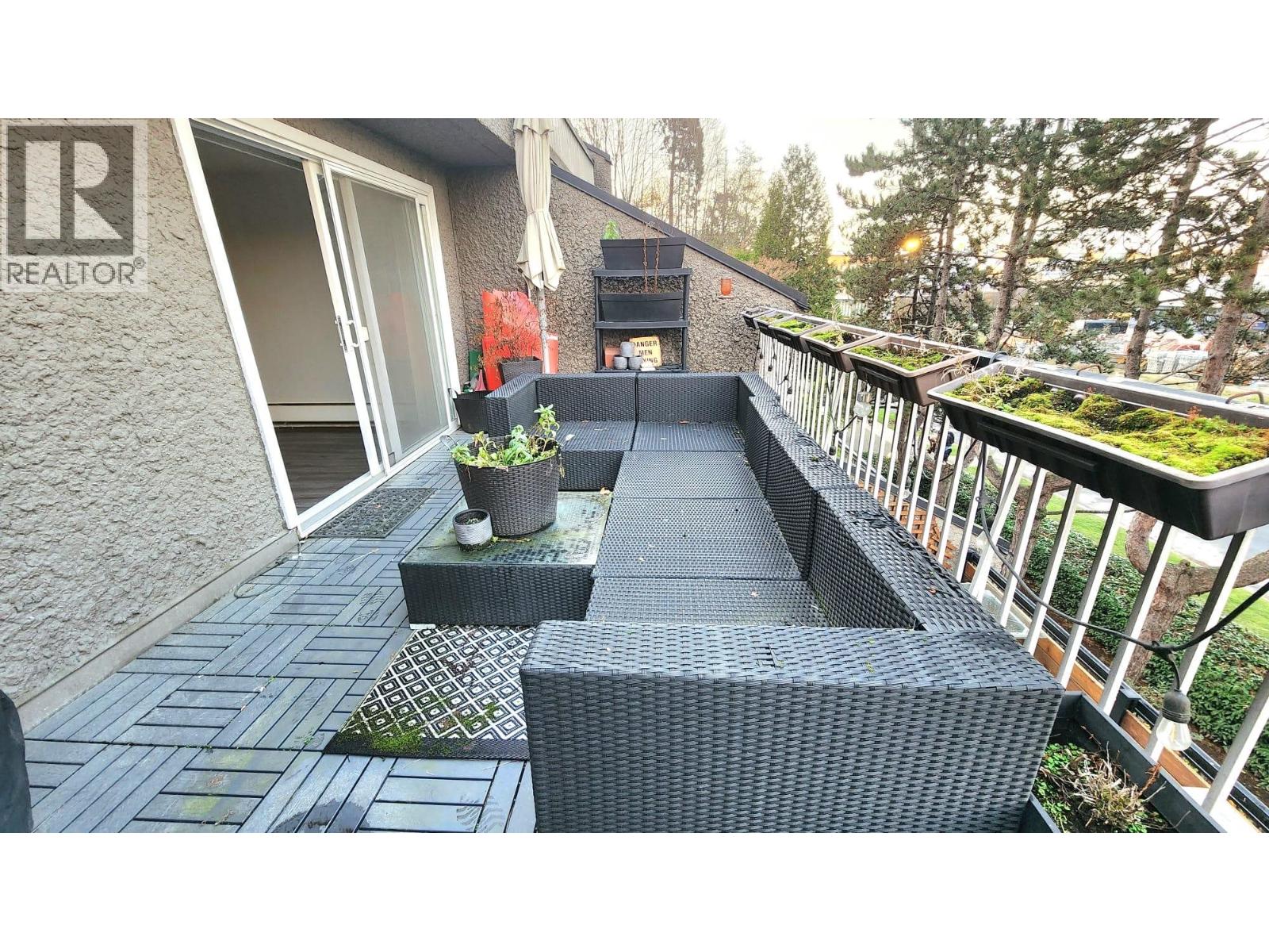 A balcony with a black wicker chair and a planter.
