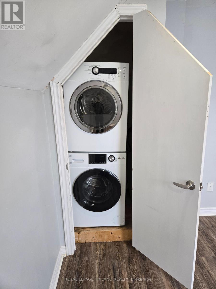 A white door is open to reveal a small laundry room with a washer and dryer.