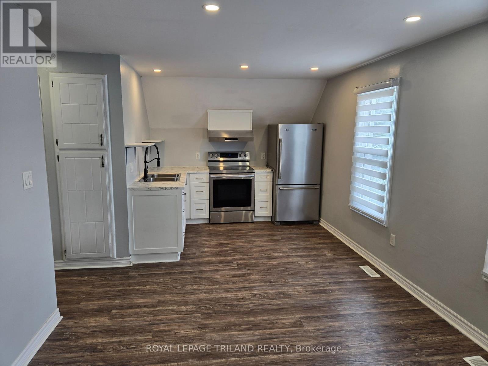 A kitchen with white appliances and wooden floors.