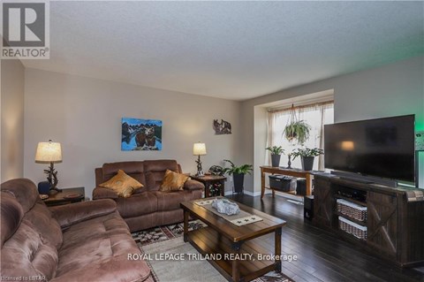 A living room with a brown couch and a painting on the wall.