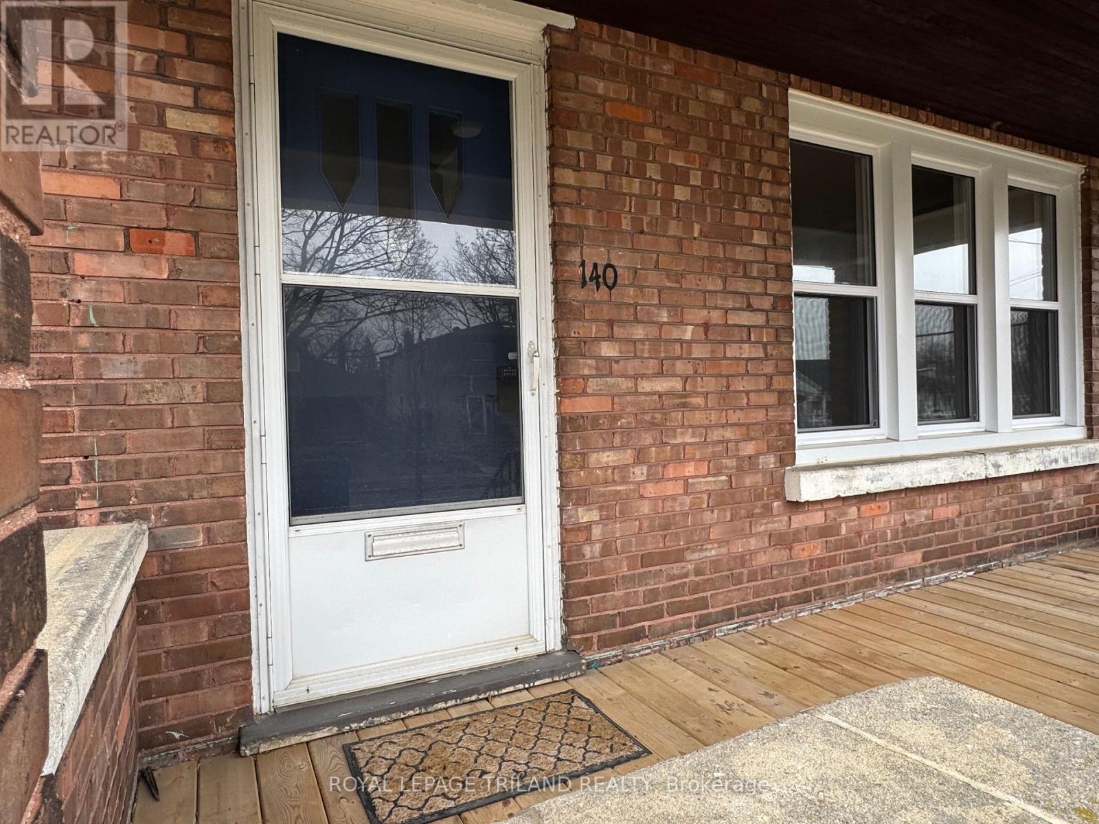 A white door with a glass window is on a brick wall.