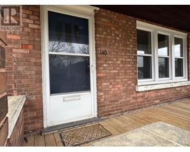 A white door with a glass window is on a brick wall.