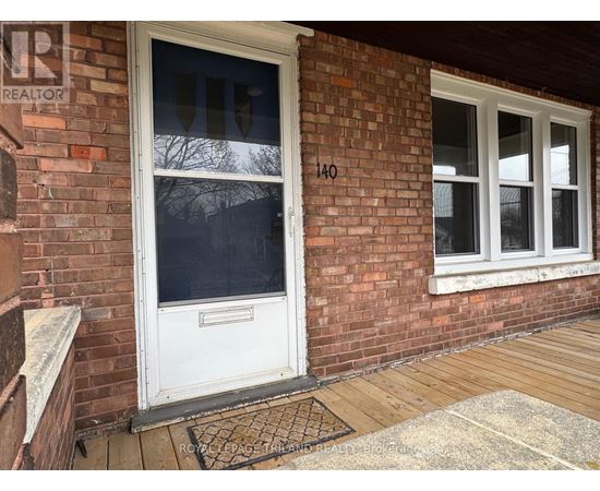 A white door with a glass window is on a brick wall.