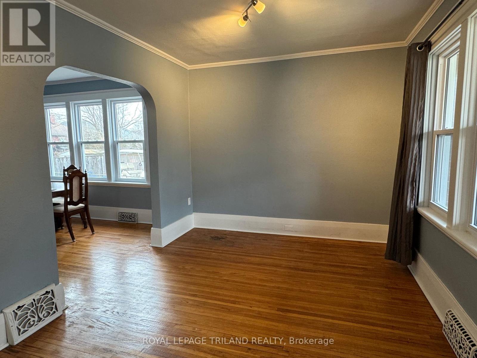 A room with wood flooring and a window with a view of trees.