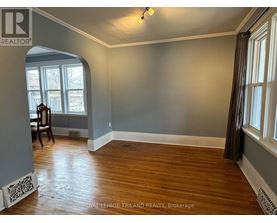 A room with wood flooring and a window with a view of trees.