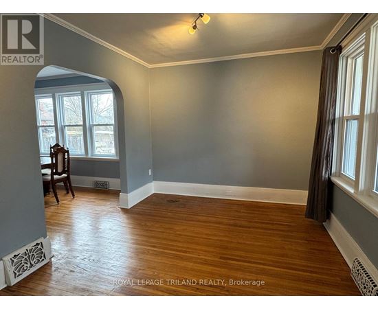 A room with wood flooring and a window with a view of trees.