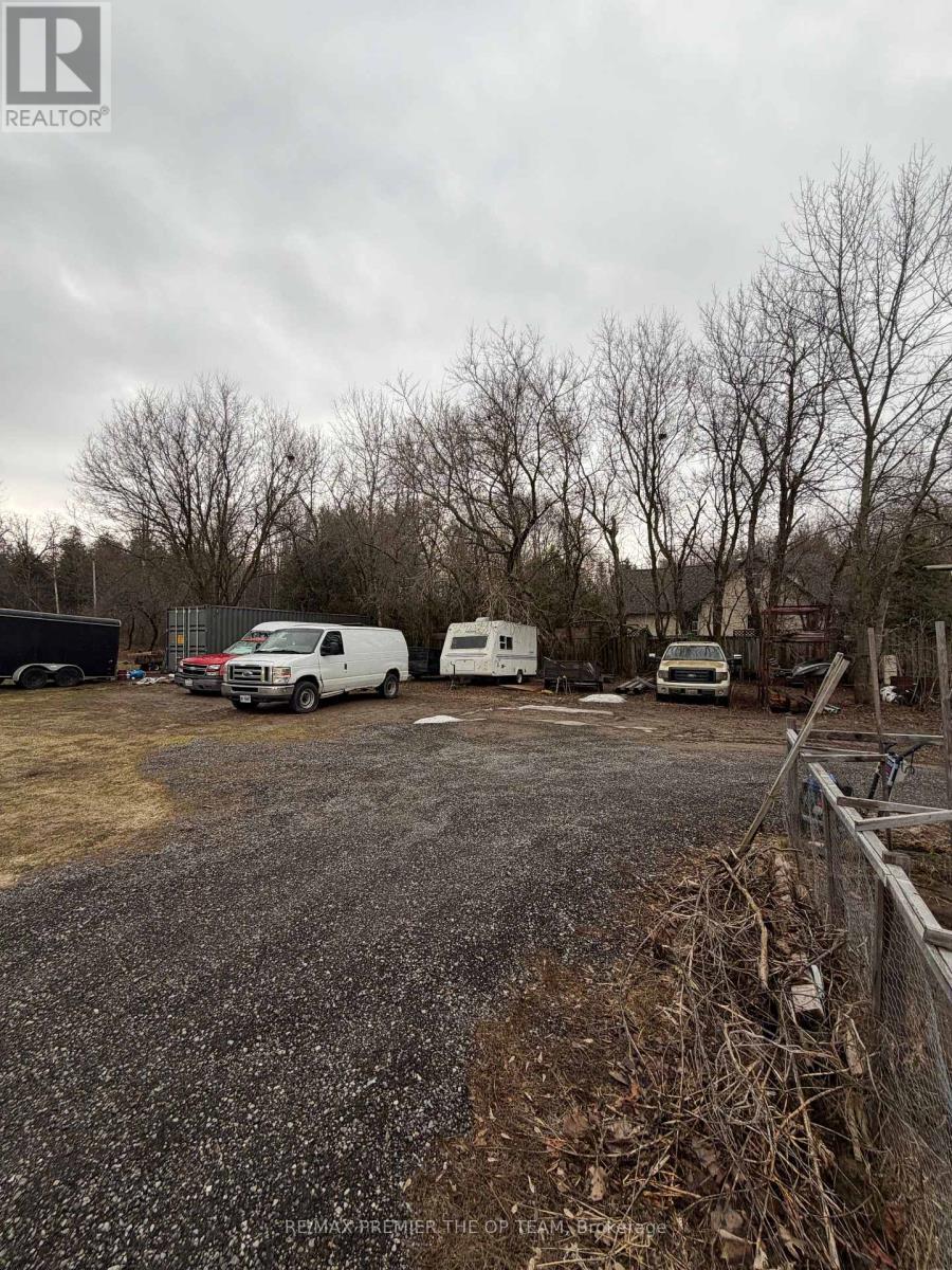 A gravel lot with a fence and a few parked vehicles.