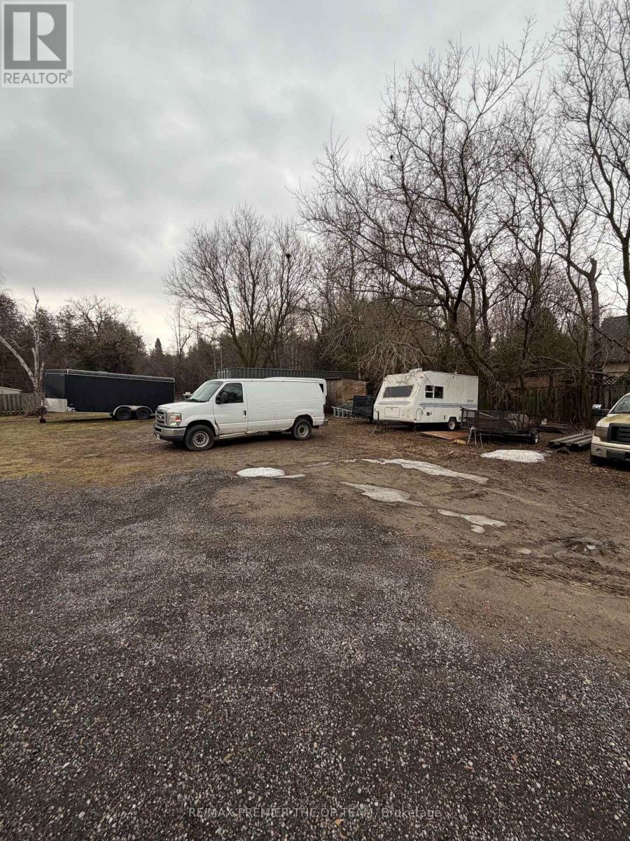 A gravel lot with a white van and a white trailer.