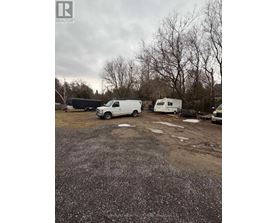 A gravel lot with a white van and a white trailer.