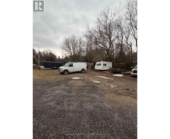 A gravel lot with a white van and a white trailer.