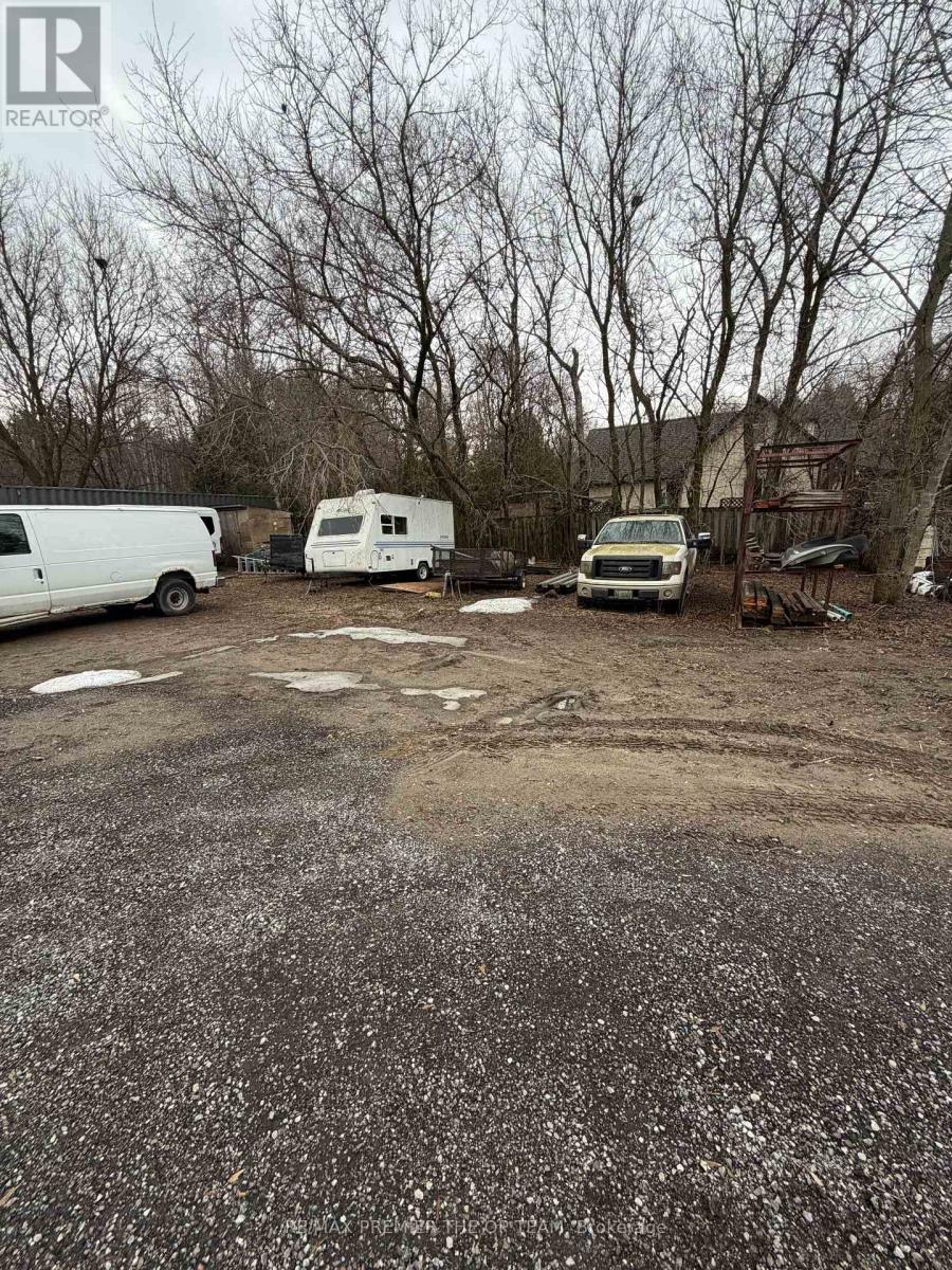 A gravel lot with a white van, a white trailer, and a white truck.