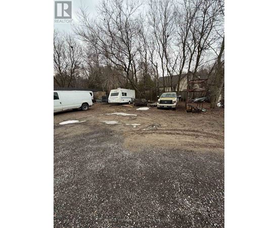 A gravel lot with a white van, a white trailer, and a white truck.