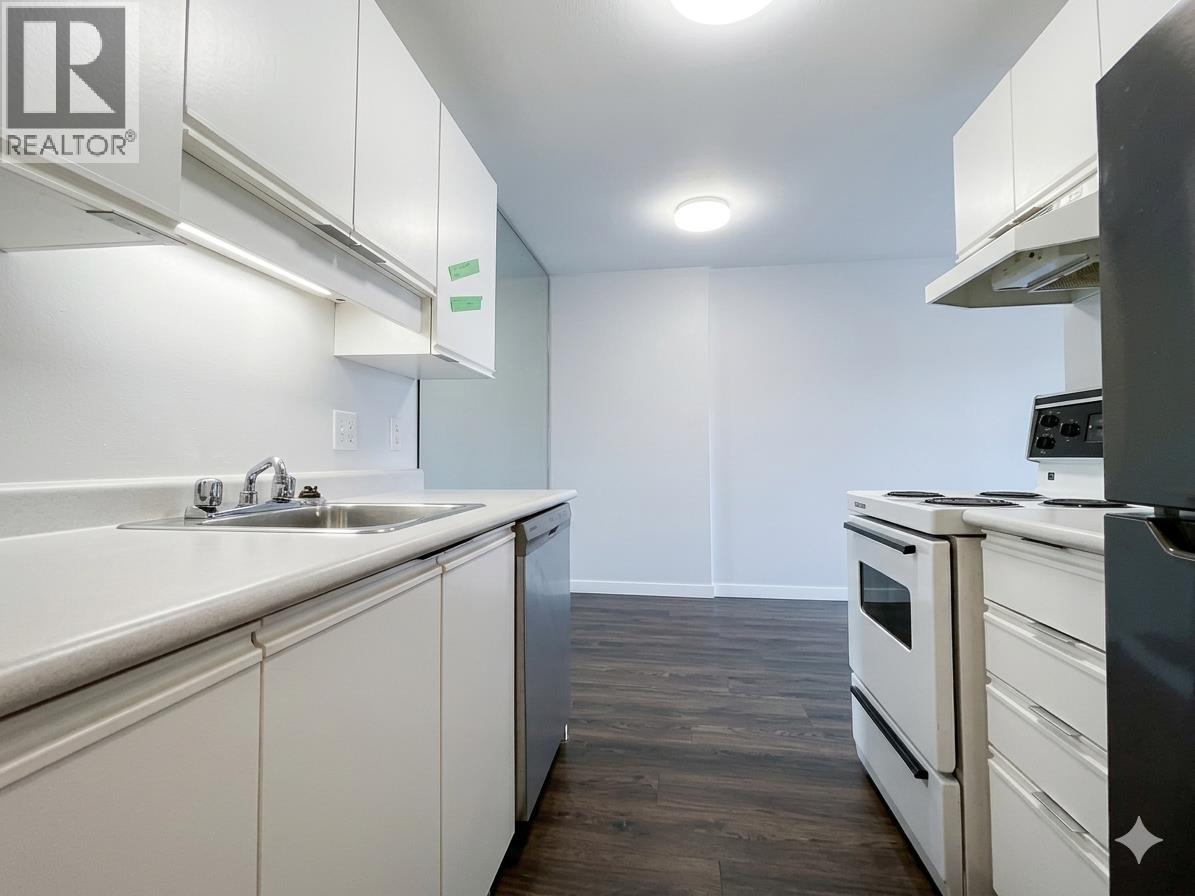 A kitchen with white cabinets and a black fridge.